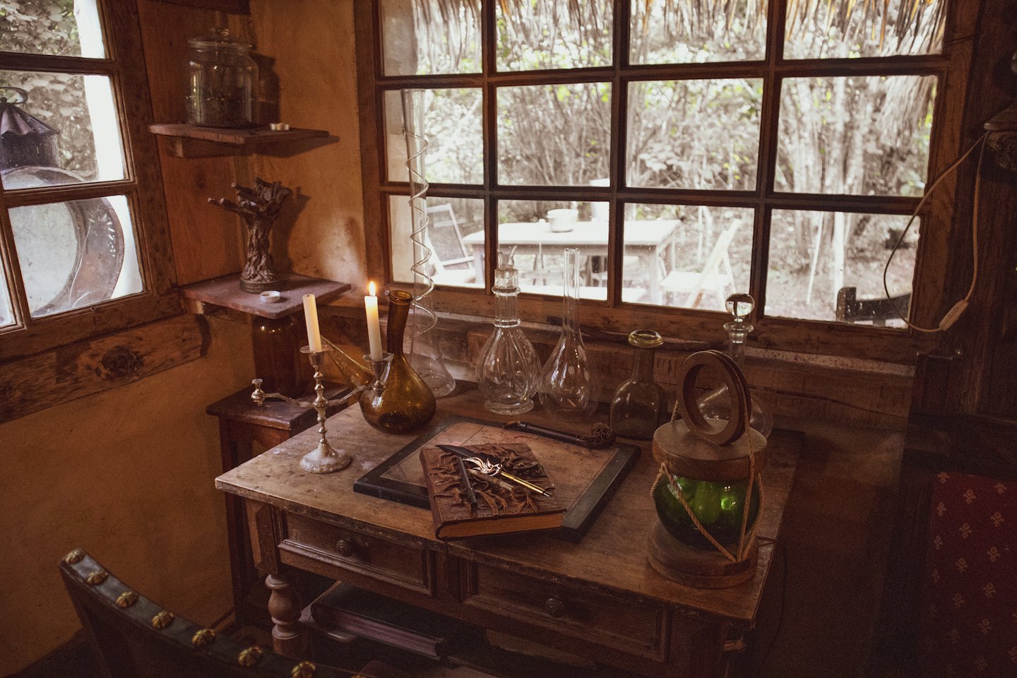 Antique objects and candles sit on a rustic wooden desk.